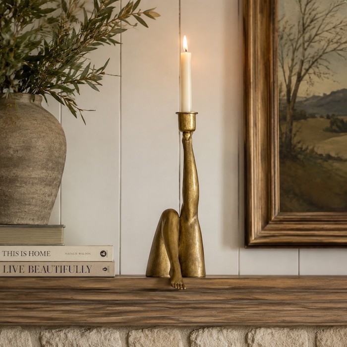 An asymmetrical display of sculptural wood and metal objects on an American farmhouse fireplace mantel