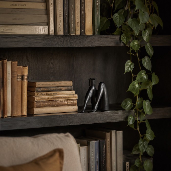A beautifully curated oak bookshelf showcasing a geometric metal candle holder between books.