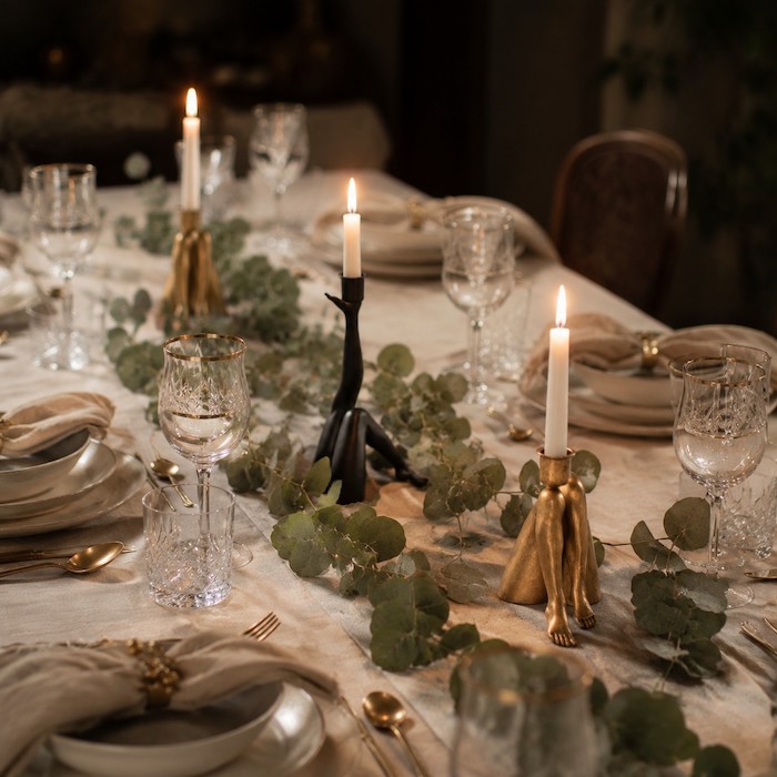 Multiple unique candle holders staggered down a long rectangular dining table.