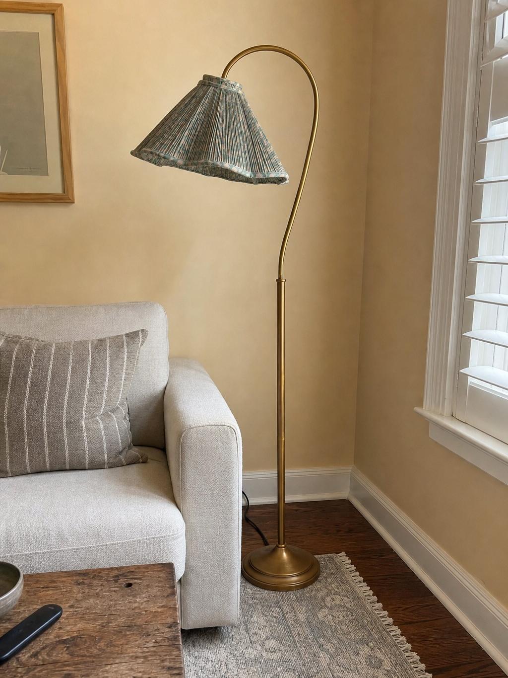 Gooseneck floor lamp beside armchair near window