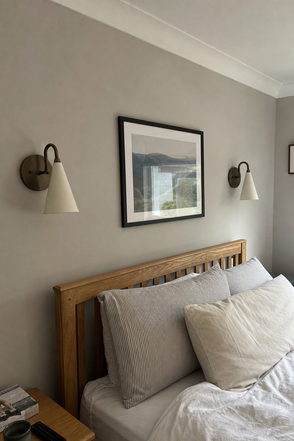 A pair of cream wall lights beside a bed