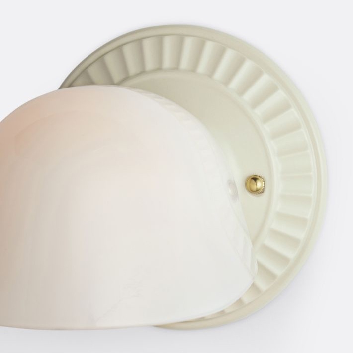 Close view of ivory fluted wall plate and white shade
