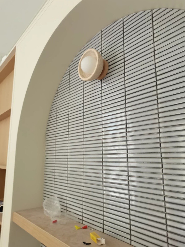 Travertine wall light on an arched tiled wall