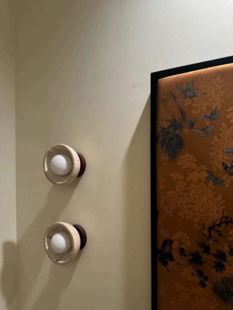 Pair of travertine wall lights beside wall art
