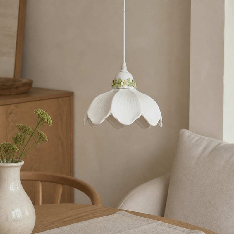 White flower pendant lamp hanging above a cozy table and chair