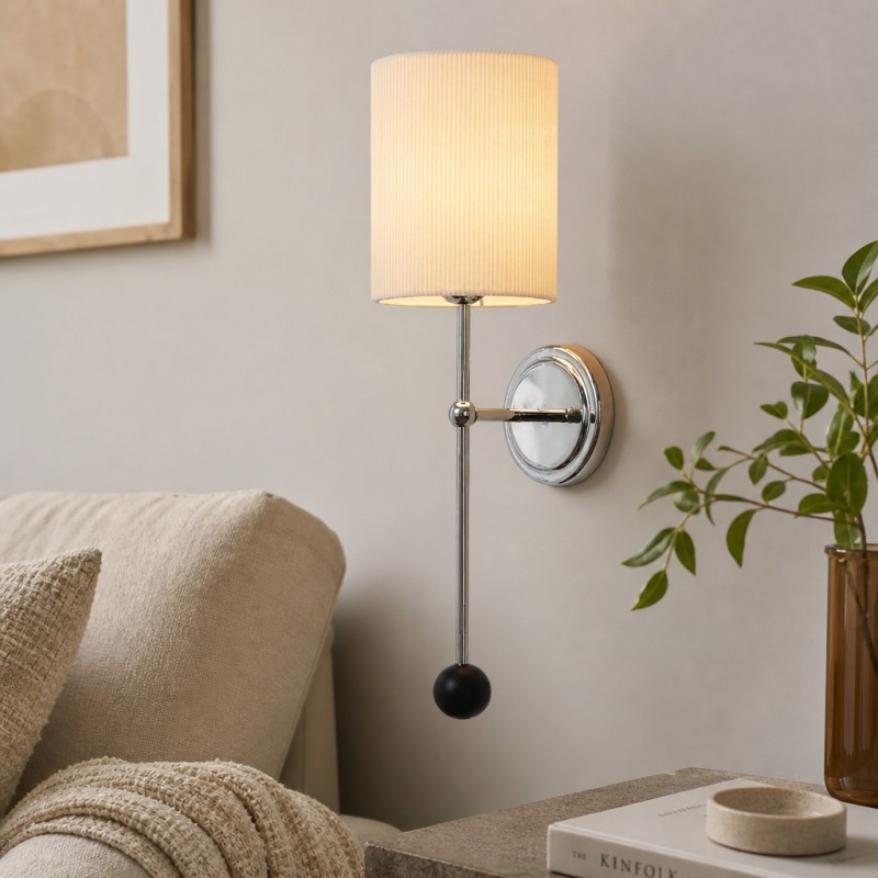 Cumoris pleated wall lamp glowing beside a sofa
