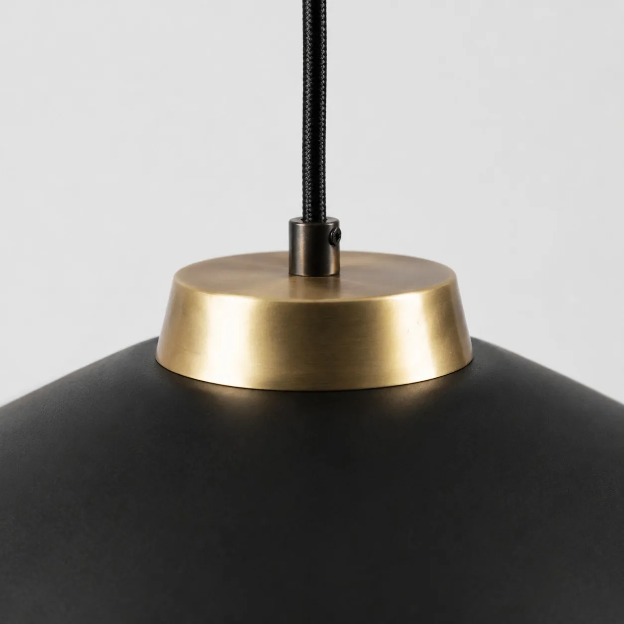 Close view of the black braided cord and brushed brass shade connector