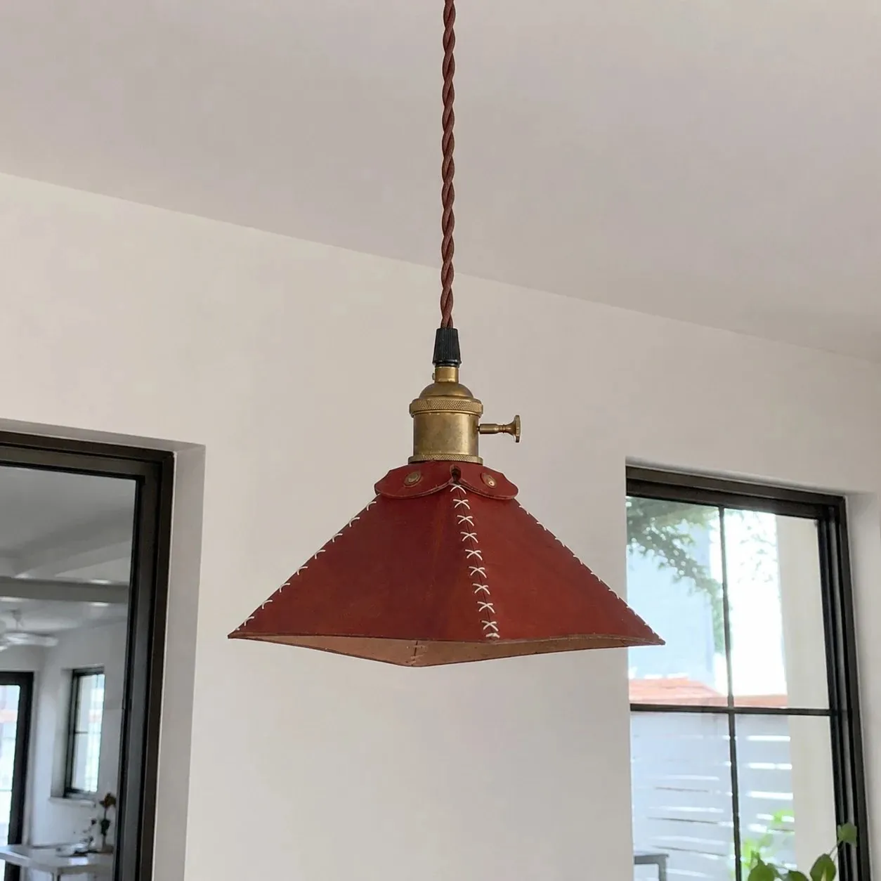 Leather pyramid pendant lamp hanging near a black framed window