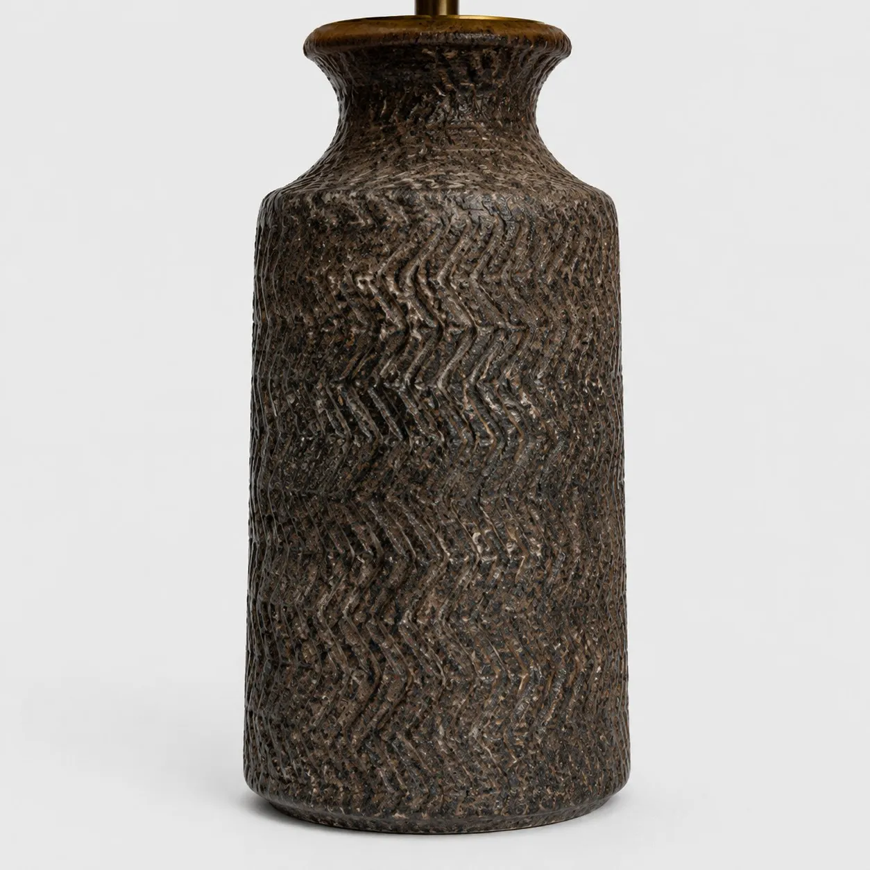 Close-up of carved wave texture on dark handmade ceramic lamp base