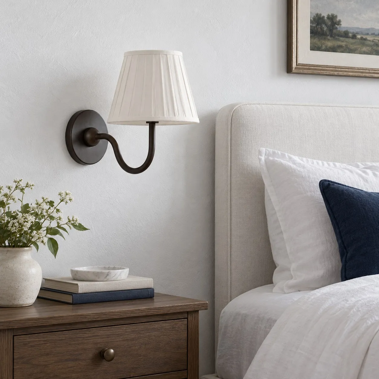 Matte black wall lamp with a white pleated shade beside a bed