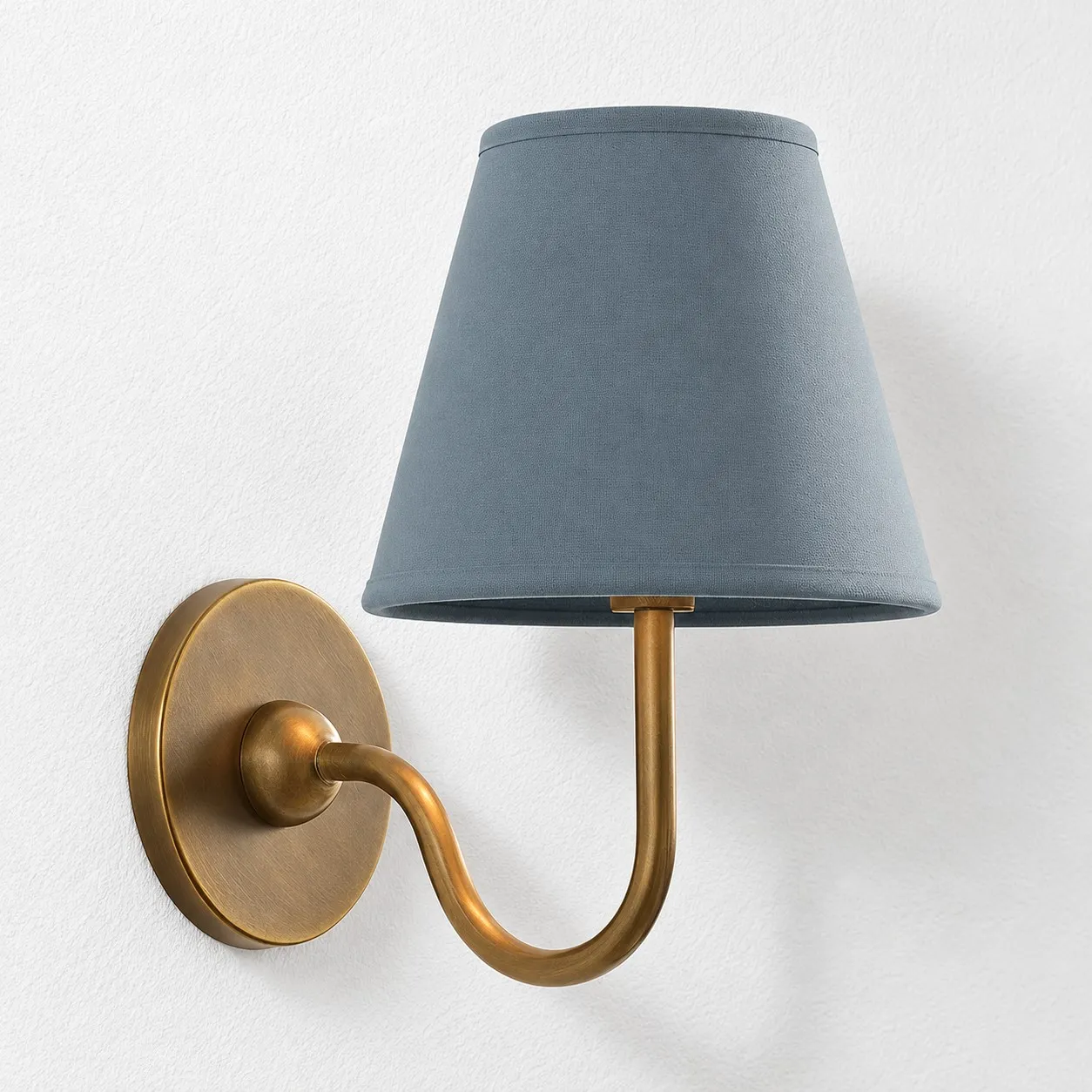Dusty blue plain linen shade on a tumbled brass wall lamp