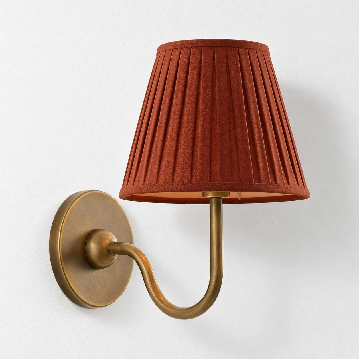 Red pleated linen shade on a tumbled brass wall lamp