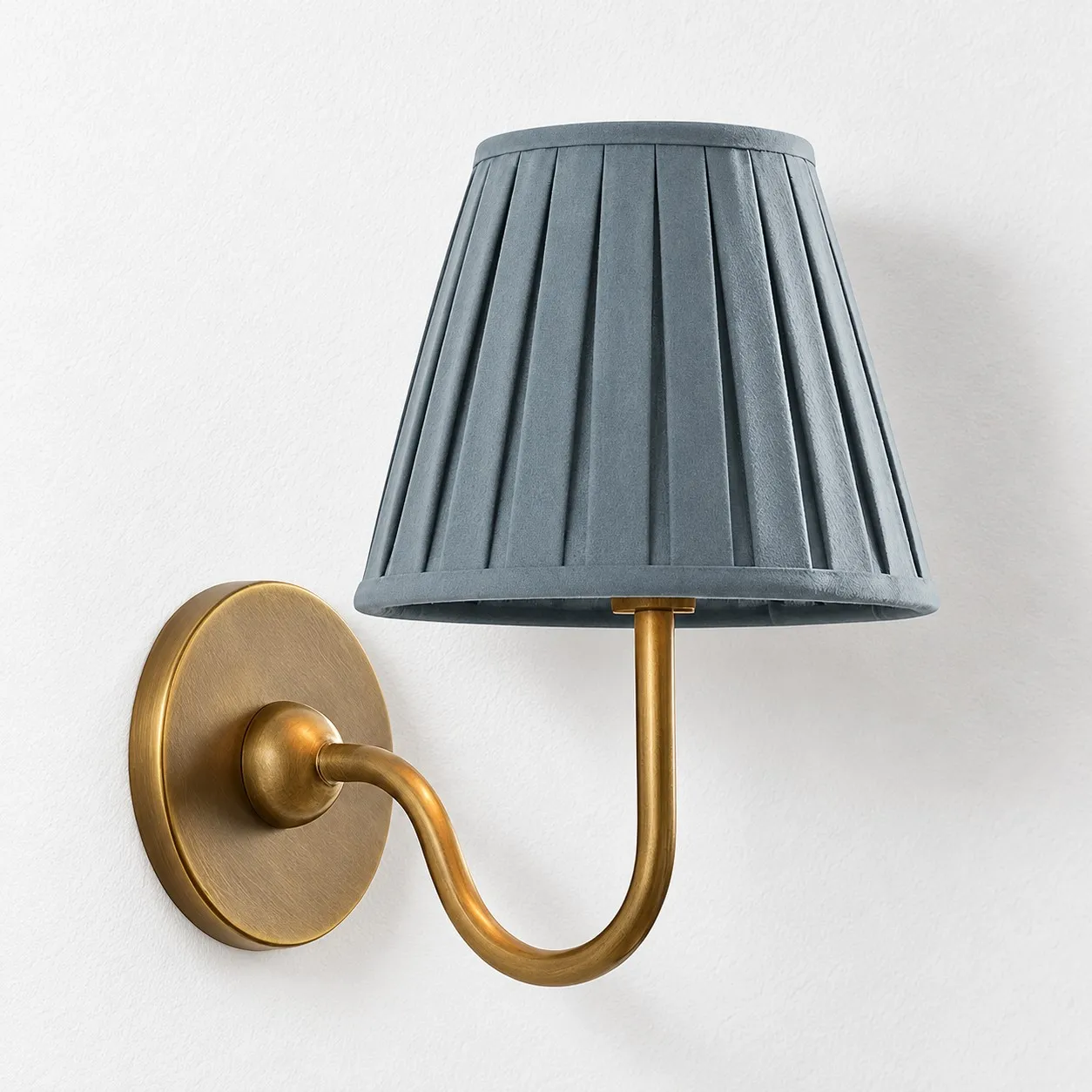 Dusty blue pleated linen shade on a tumbled brass wall lamp