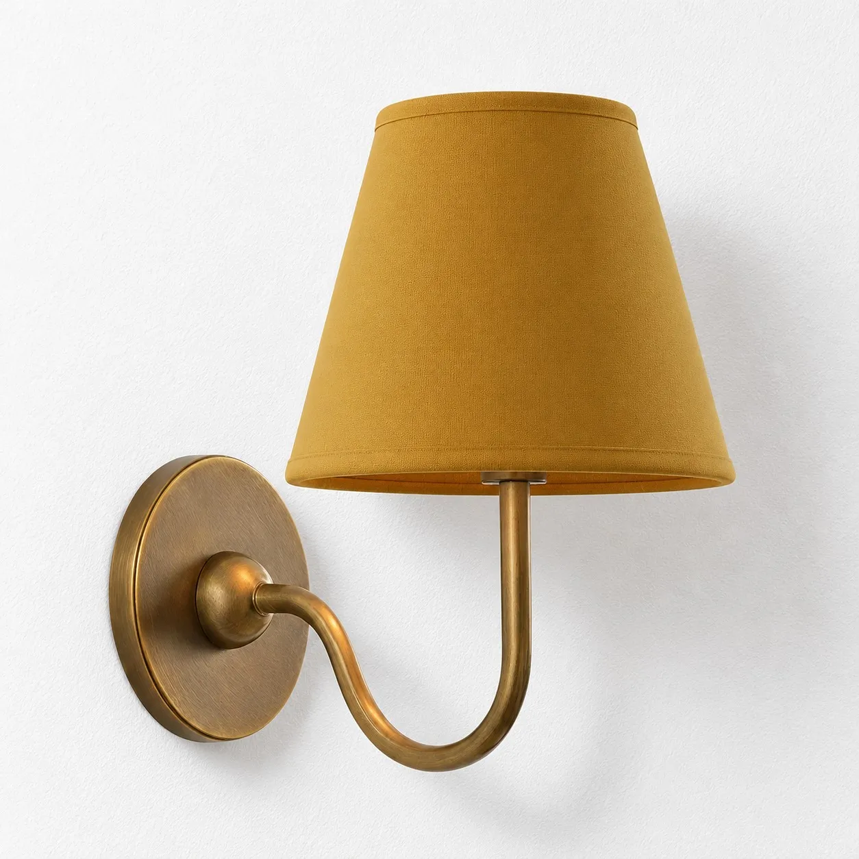 Mustard yellow plain linen shade on a tumbled brass wall lamp