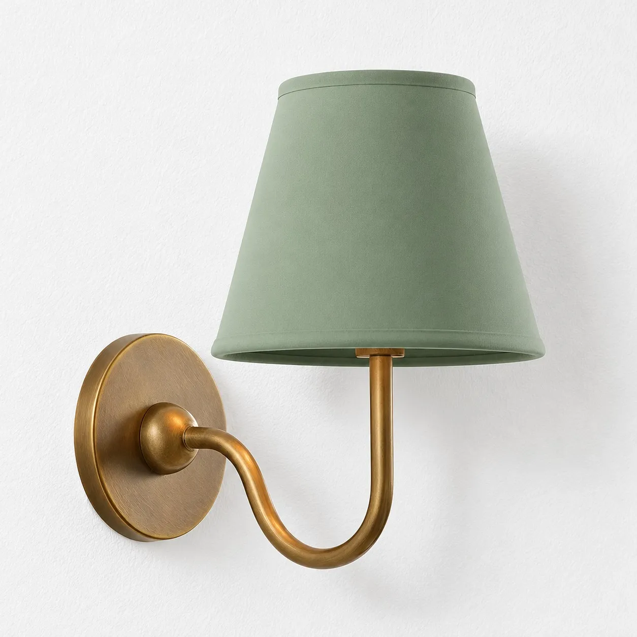 Sage green plain linen shade on a tumbled brass wall lamp