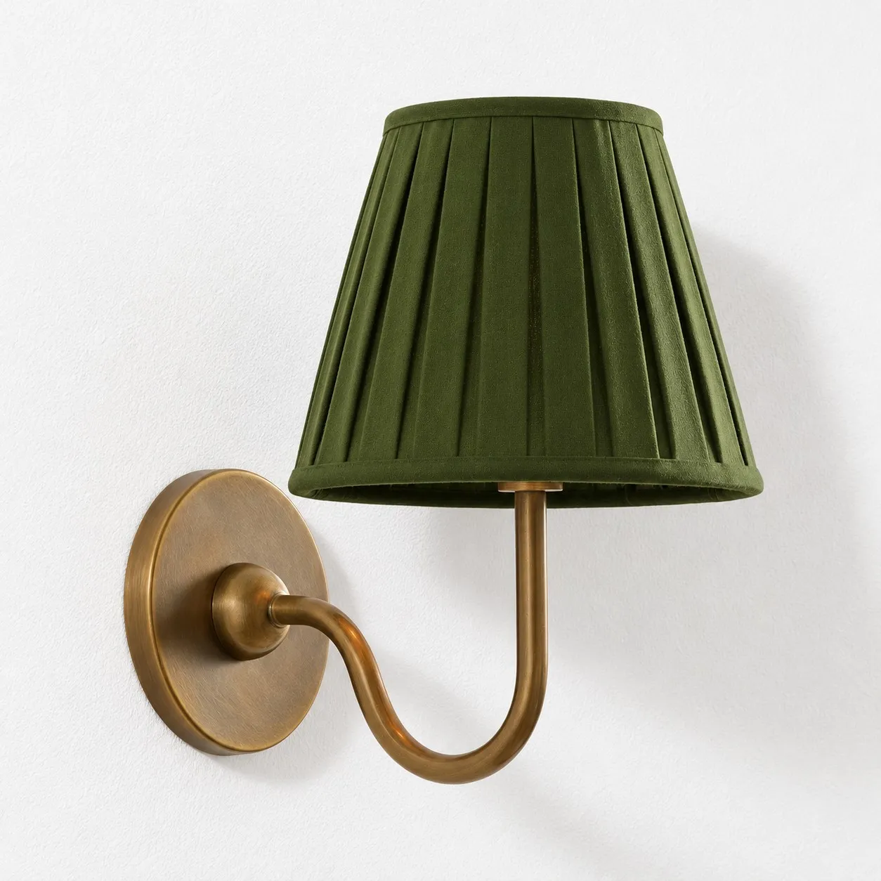 Green pleated linen shade on a tumbled brass wall lamp