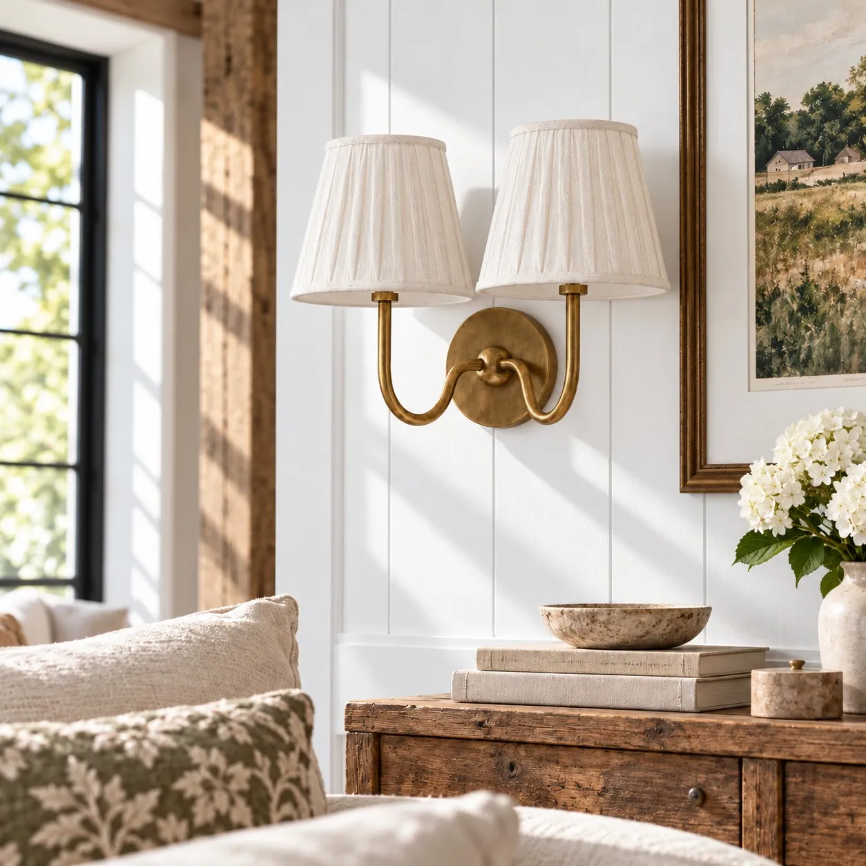 Tumbled brass wall lamp with a white pleated shade in a living room