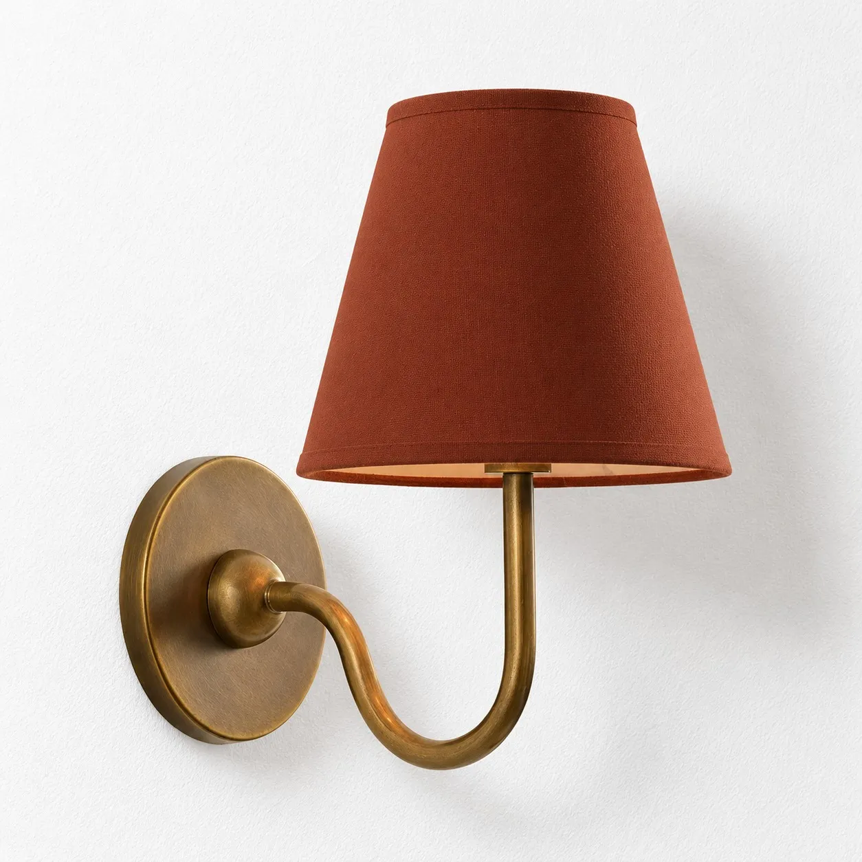 Red plain linen shade on a tumbled brass wall lamp